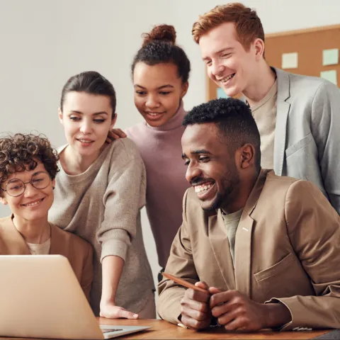 Group of volunteers smiling and looking at a computer